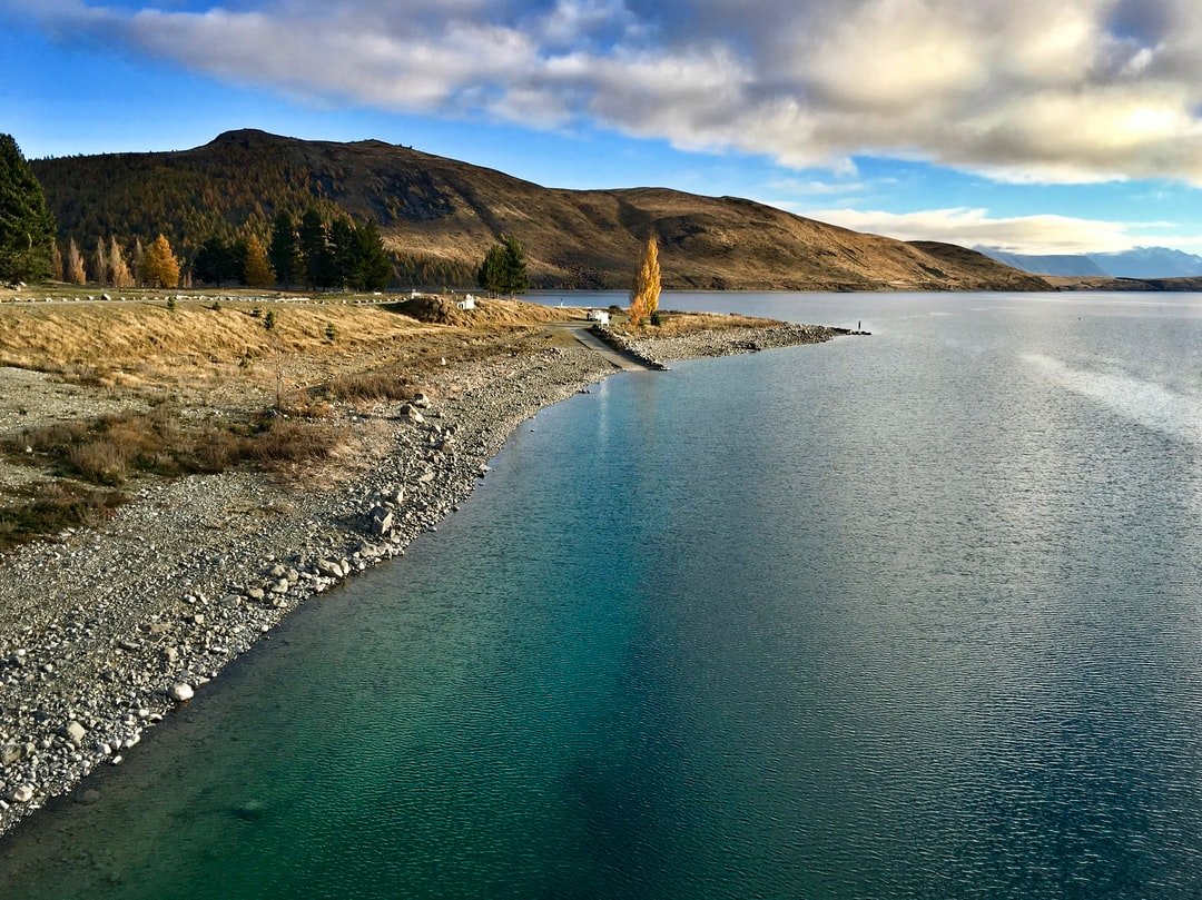 One of the most picturesque locations in New Zealand, Lake Tekapo rests peacefully next to the township of Tekapo. The hill on the other side of the lake is the site of the Mount John observatory, an observatory with almost unparalleled views of the stars in the dark sky reserve above.  | Lake Tekapo in New Zealand
