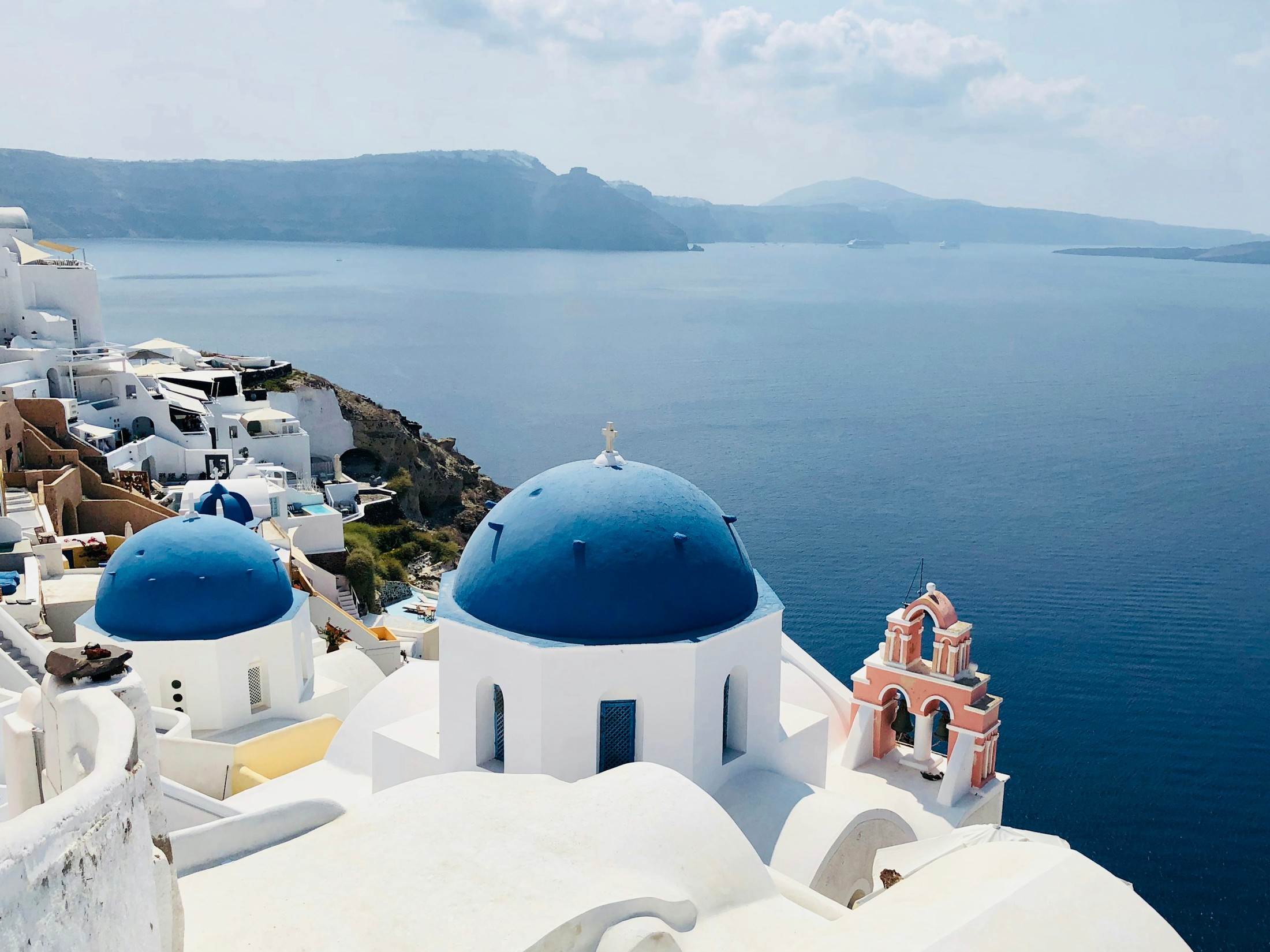 Overlooking the famous blue church domes in the town of Oia, isle of Santorini, Greece. | Oia in Greece