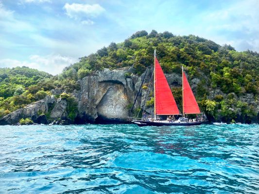 Photograph of red sailboat beside Maori carving in Lake Taupo in New Zealand | Taupo in New Zealand