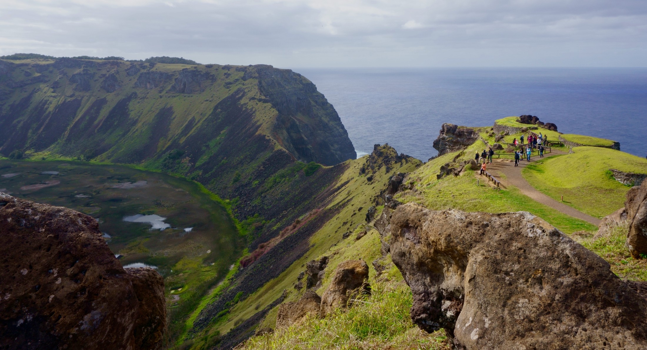 A view from the west side of the crater at Rano Kau, looking towards the southern side of the crater, where much of the crater wall has collapsed into the sea. On the right side of this photo is the Orongo Ceremonial Village. | Easter Island in Chile